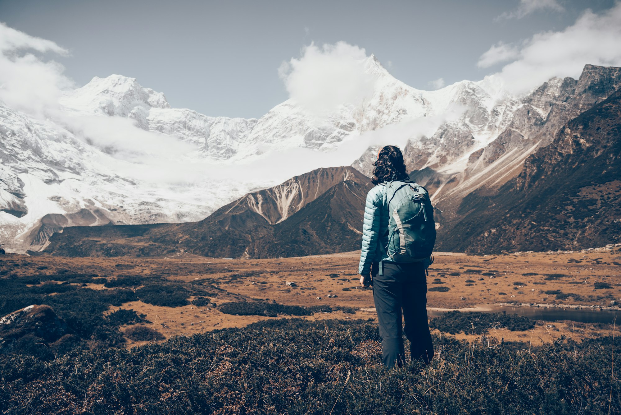 Standing young woman with backpack and mountains